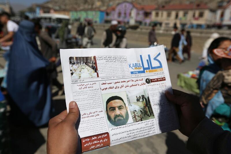 FILE - In this May 25, 2016, file photo, an Afghan man reads a local newspaper with photos the former leader of the Afghan Taliban, Mullah Akhtar Mansoor, who was killed in a U.S. drone strike last week, in Kabul, Afghanistan. A Pakistani judge ordered the auction of five properties purchased by former Taliban chief Mullah Akhtar Mansour with fake documents before he was killed in a U.S. drone strike in 2016, two investigators familiar with the case said Friday, May 8, 2020. (AP Photo/Rahmat Gul, File)