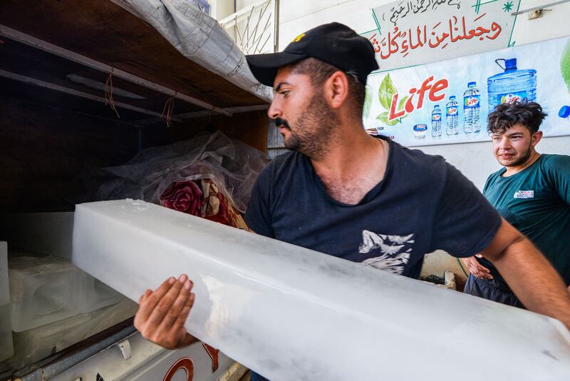 An Iraqi worker loads ice blocks into a customer's pick-up truck at a factory in the northern city of Mosul, amid power outages and soaring temperatures.