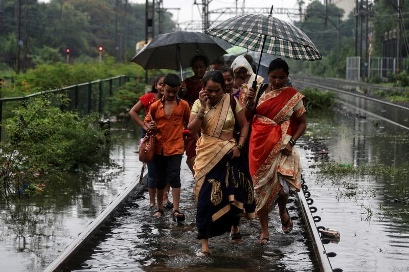 Commuters walk on waterlogged railway tracks after getting off a stalled train during heavy monsoon rains in Mumbai. Reuters