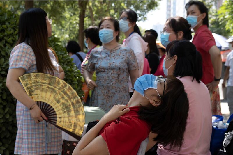Parents wearing masks to limit the spread of the coronavirus wait in the shade as their children take part in their college entrance exams in Beijing, China. AP Photo