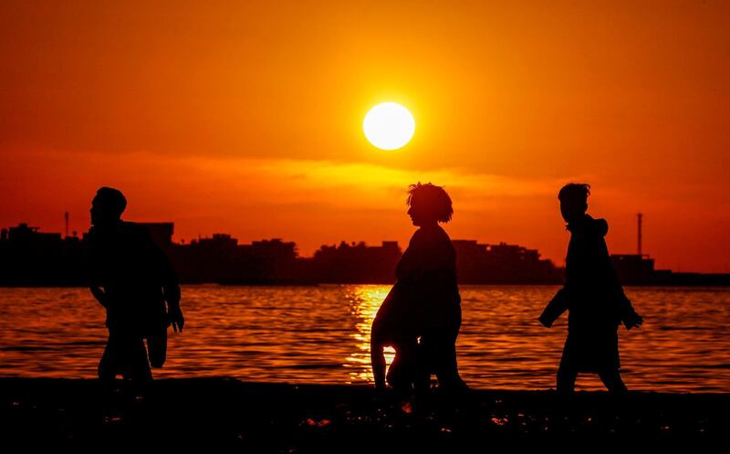 Libyan youths walk along a beach near sunset in the capital Tripoli.   AFP