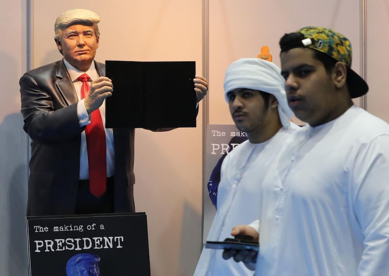 Two Emirate boys walk past a statue of US President Donald Trump.