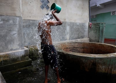 A Sri Lankan man takes a bath at a public well at Wanathamulla, Colombo in August 2022. Reuters 