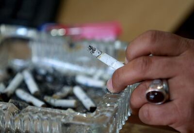 A Jordanian man holds his cigarette over an ashtray in the Jordanian capital Amman, on March 17, 2021.  With already one of the world's highest rates of smokers, Jordan has seen the numbers lighting up soar since coronavirus restrictions began last year, a health crisis worrying medics. / AFP / Khalil MAZRAAWI
