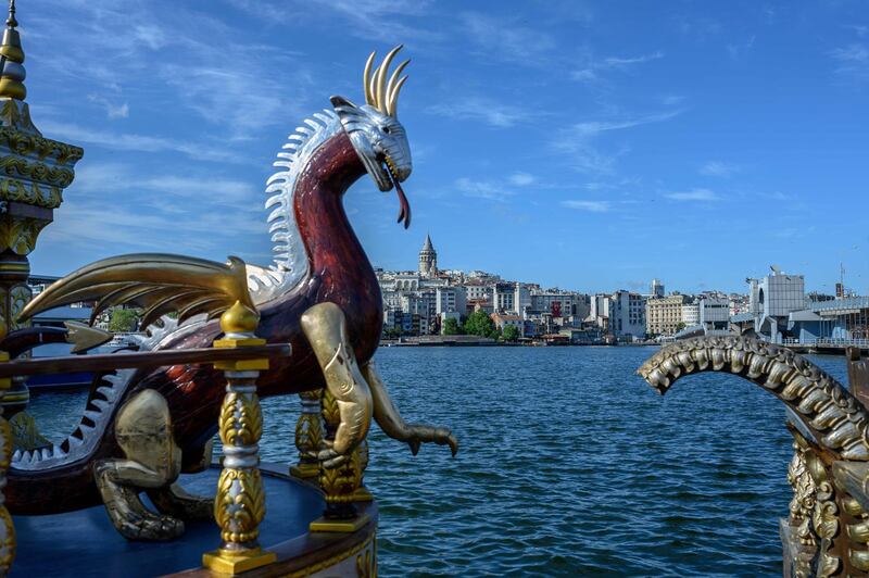 A picture shows a dragon sculpture decorating an empty fish sandwich boat and the Galata Tower in the background in Istanbul on the third day of Eid Al Fitr. AFP