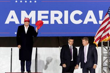 Former U. S.  President Donald Trump holds up MAGA caps during his rally in Florence, Arizona, U. S. , January 15, 2022.   REUTERS / Carlos Barria