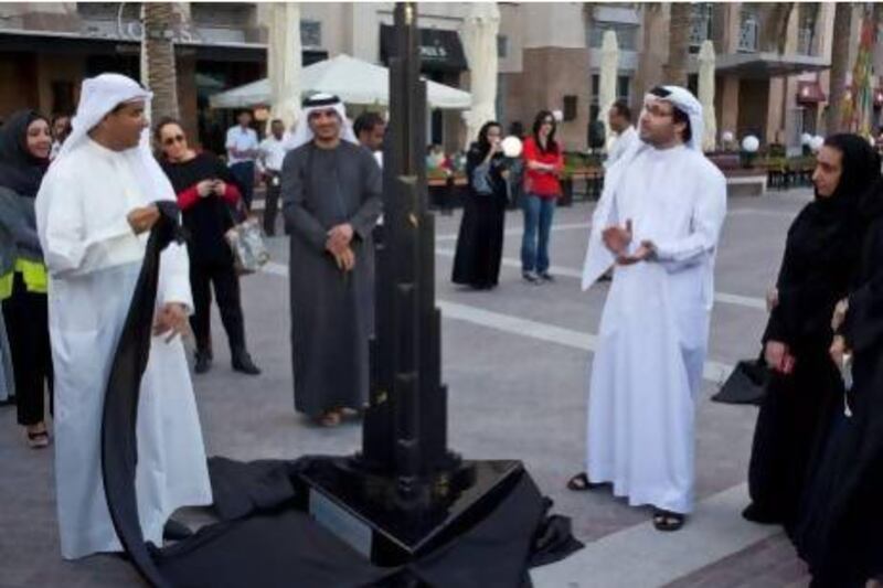 Mohamed Alabbar, founding member and Chairman of Emaar Properties (left) and Tariq Al Gurg, CEO of Dubai Cares (right) unveil the artwork of Emirati artist, Maryam Al Sayegh, as part of the the Burj of Giving auction in benefit of Dubai Cares. Twenty-one artistically adorned Burj Khalifa scale models were auctioned off to raise funds for developing nations. Antonie Robertson / The National