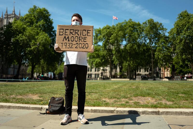 LONDON, UNITED KINGDOM - MAY 20: Ellis Tustin, the Grandson of Berrice Moore, holds up his Grandfather's name as he stages a personal protest to Prime Minister Boris Johnson outside the Houses of Parliament on May 20, 2020 in London, United Kingdom. Tustin believes that the Government is forgetting that each of the figures listed in the daily COVID-19 death toll update is a real person, so displays the name as Johnson passes on the way to and from the weekly PMQ session. The British government has started easing the lockdown it imposed two months ago to curb the spread of Covid-19, abandoning its 'stay at home' slogan in favour of a message to 'be alert', but UK countries have varied in their approaches to relaxing quarantine measures. (Photo by Leon Neal/Getty Images)