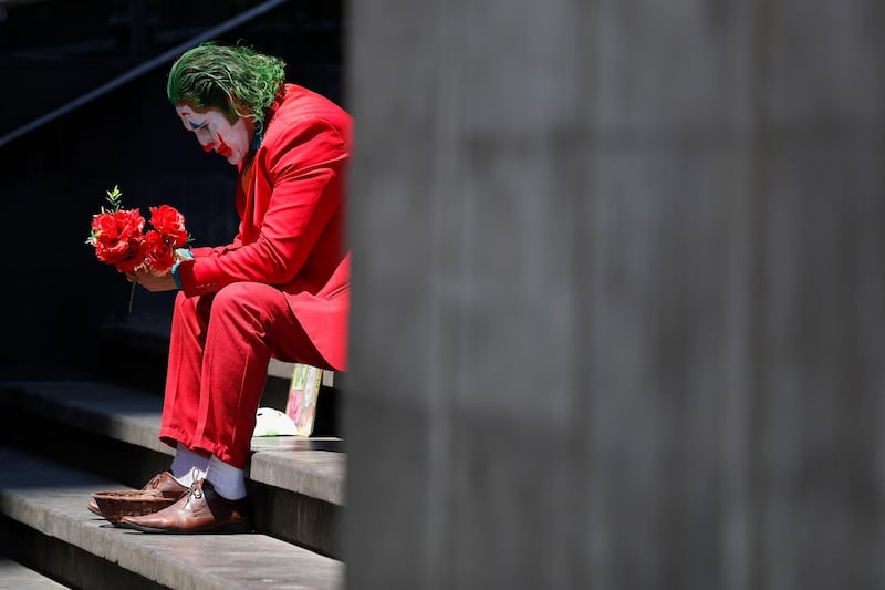 David Vazquez, a street performer dressed as the Joker, waits in hopes of pedestrians who will pay to take pictures with him in Mexico City. AP Photo