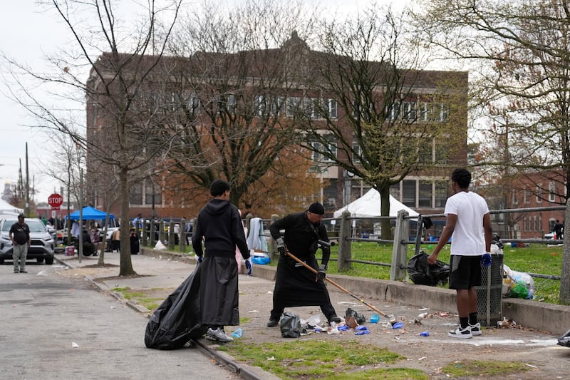 People clean up debris at the scene of a shooting