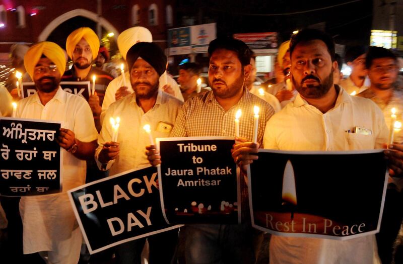 Members of the National Human Rights and Crime Control Organisation hold candles and signs during a condolence and tribute paying ceremony for the victims of a train accident in Amritsar, India. EPA