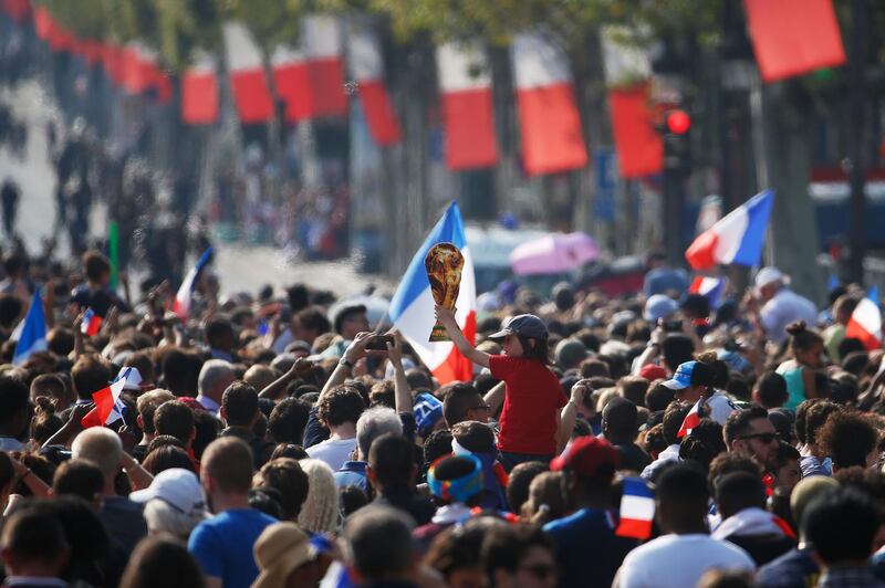 A child holds a placard shaped as a the World cup trophy as he waits with other supporters 
on the Champs-Elysees avenue in Paris on July 16, 2018, for the arrival of the French national football team for celebrations after France won the Russia 2018 World Cup final football match on the previous night. / AFP / CHARLY TRIBALLEAU
