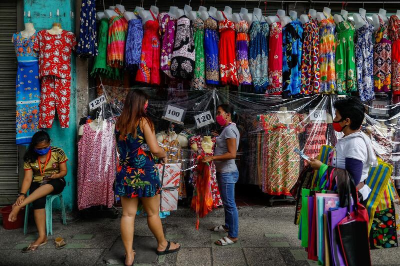 A woman buys a dress in a street market on the first day of the Philippine capital's gradual reopening since the lockdown.  Reuters