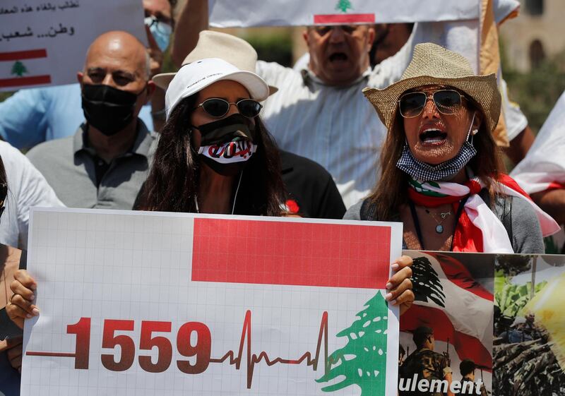 Anti-Hezbollah protesters shout slogans and hold a placard with the UN Resolution 1559, which was adopted in September 2004, that called for disarmament all Lebanese and non-Lebanese militias, during a sit-in against Hezbollah and Iran in front the United Nations headquarters, in Beirut, Lebanon.  AP
