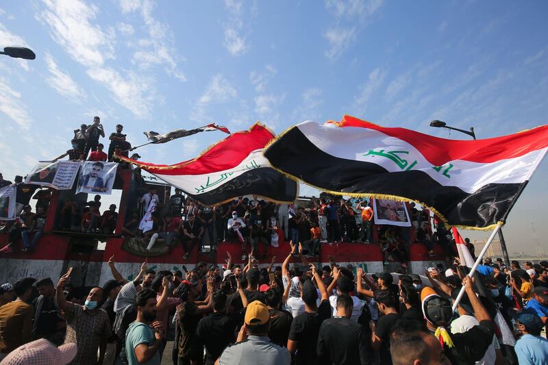 Iraqi demonstrators wave flags as they gather in Tahrir Square to mark the first anniversary of a massive anti-government movement demanding the ouster of the entire ruling class accused of corruption. AFP