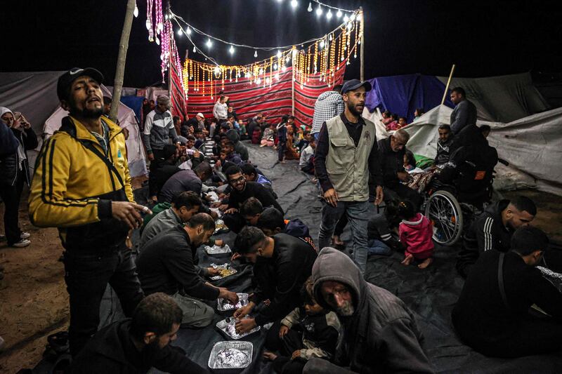 Palestinians share an iftar meal, the breaking of fast, on the first day of the Muslim holy fasting month of Ramadan, at a camp for displaced people in Rafah in the southern Gaza Strip. AFP
