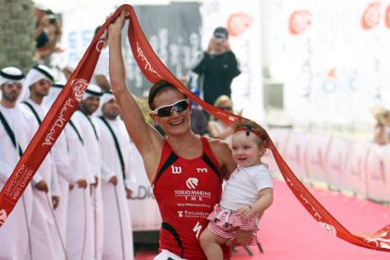 Nikki Butterfield carries her daughter, Savanah, across the finish line to help her celebrate taking the women's elite title at the Abu Dhabi International Triathlon.