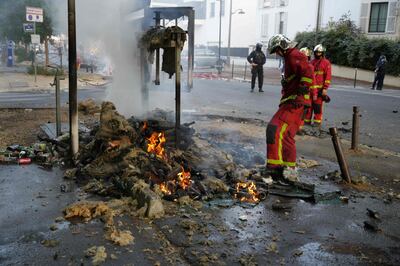 Firefighters work to put out burning objects in the street after a demonstration in Nanterre. AFP