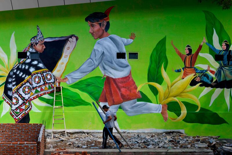An artist works to complete a mural on the premises of an art department building in Banda Aceh, Indonesia. AFP