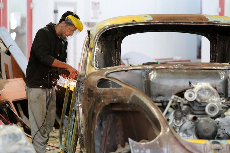 A mechanic works on a Ford Mercury Beatle.