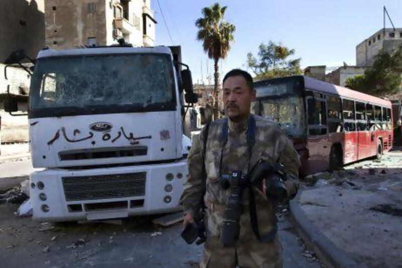Toshifumi Fujimoto, pictured in front of damaged buses in Aleppo’s old city, plans to visit the Taliban in Afghanistan next.