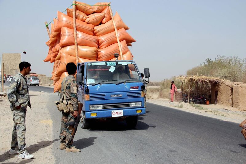 Afghan security officials check people at a checkpoint in Helmand.  EPA