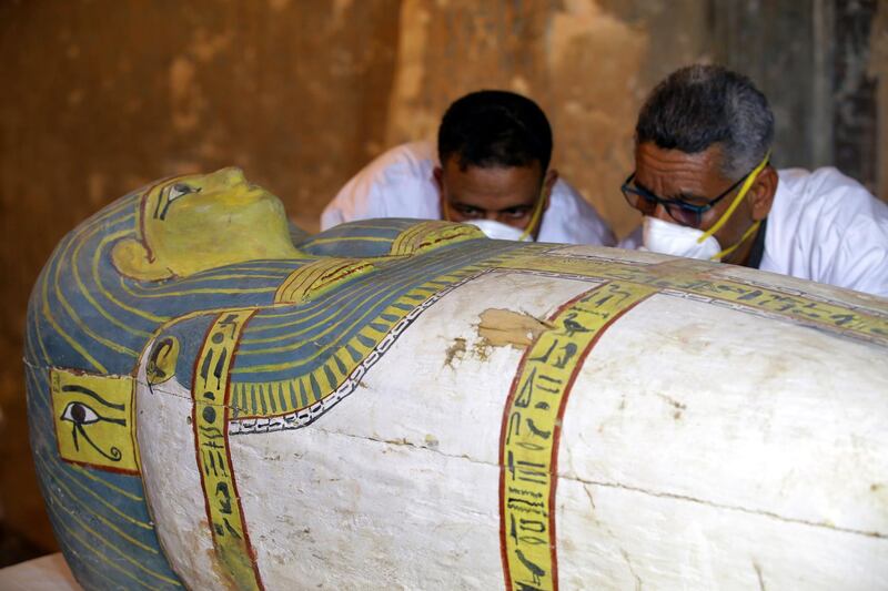 Egyptian archaeologists move the cover of an intact sarcophagus. EPA