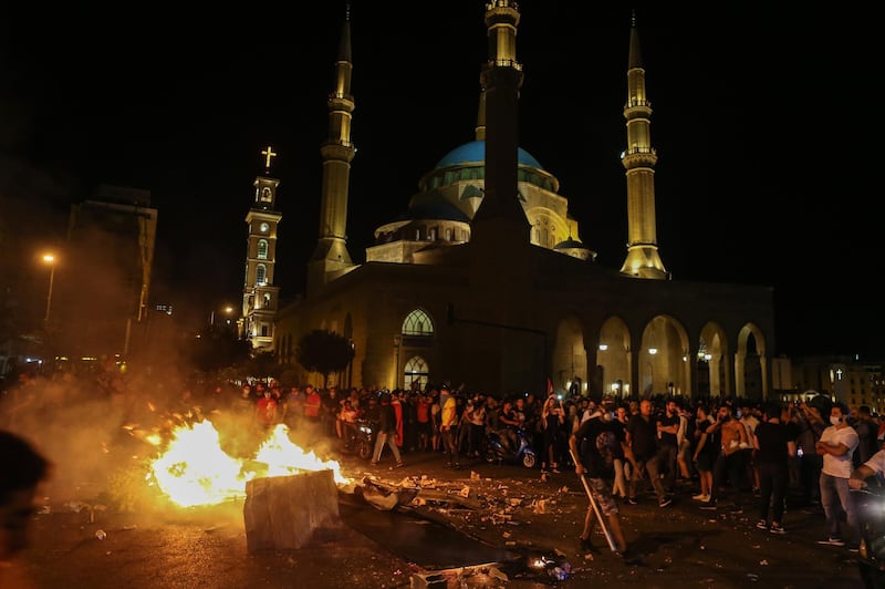 Protesters throw wood on a fire to block the area in front Al-amen mosque during a protest in north of Beirut, Lebanon.  EPA