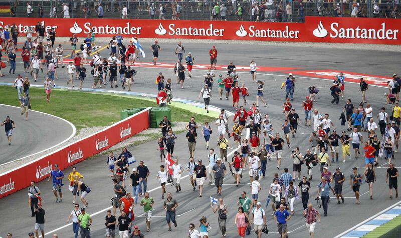 Spectators run over the race track to attend the victory ceremony after the German F1 Grand Prix. Reuters