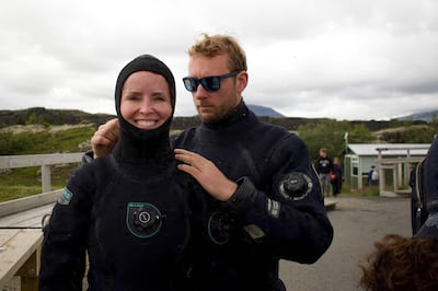 Diving instructor Lorenzo helps a tourist put on her hood before venturing into the icy waters. AFP