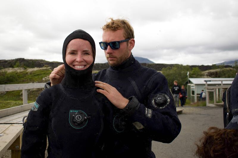 Diving instructor Lorenzo (R) helps a Canadian tourist (L) to put on her hood before a snorkelling tour on July 26, 2022 in Thingvellir, Iceland.  - In between North American and Eurasian tectonic plates, Iceland's Silfra fissure is one of the world's most famous dive sites, popular with tourists who venture into its icy waters.  (Photo by Jeremie RICHARD  /  AFP)  /  TO GO WITH AFP STORY BY JEREMIE RICHARD