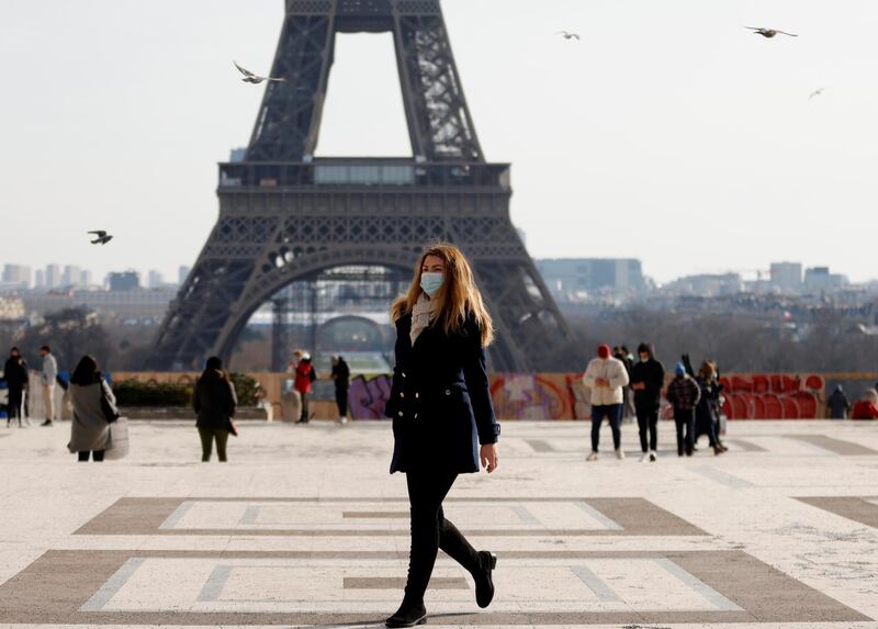 A woman, wearing protective face masks, walks in front of the Eiffel tower at the Trocadero in Paris amid the coronavirus disease (COVID-19) outbreak in France, February 11, 2021. REUTERS/Sarah Meyssonnier