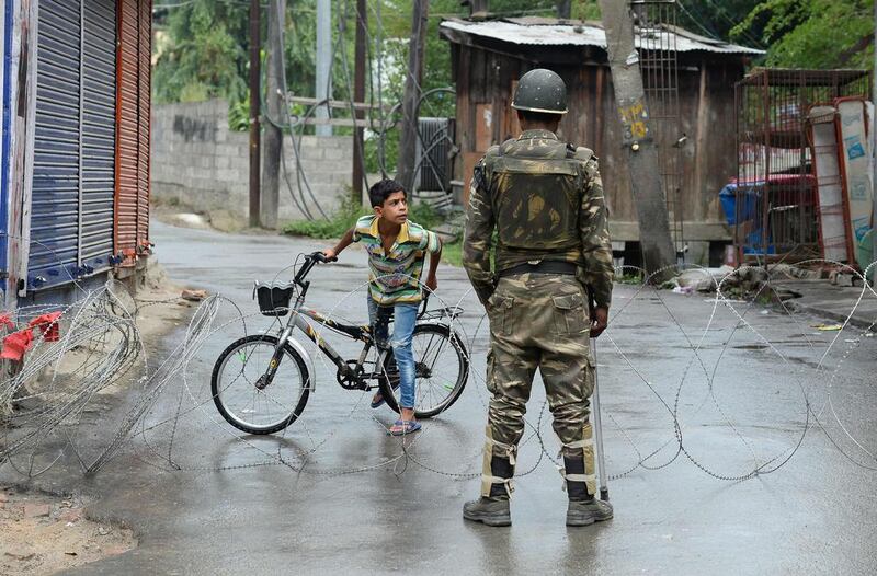 An Indian paramilitary trooper stands guard as a Kashmiri child looks out from behind a barbed wire cordon during a curfew in Srinagar. Sajjad Hussain / AFP