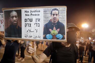 A Protester holds a portrait of Eyad Hallaq, a Palestinian killed recently by Israeli border police officers, and George Floyd who was killed during a police arrest in the US, during a rally on Saturday rally in Tel Aviv against Israel's plans to annex parts of the West Bank. AP