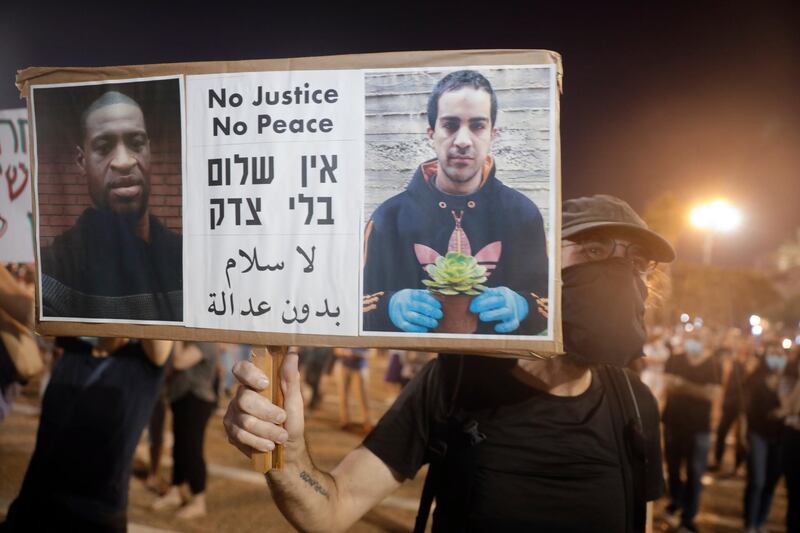 Protesters attend a rally against Israel plans to annex parts of the West Bank, in Tel Aviv, Israel, Saturday, June 6, 2020. Protester holds a portrait of Eyad Hallaq, on the right, a Palestinian with severe autism who was killed recently by Israeli border police officers after a chase in Jerusalem's Old City after apparently being mistaken as an attacker, and George Floyd who was killed during a police arrest in Minneapolis, Minnesota, May 25, 2020. (AP Photo/Sebastian Scheiner)
