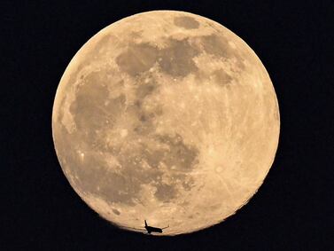 A plane is silhouetted against the Worm Moon in 2022. AFP