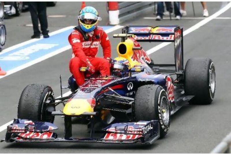 Fernando Alonso, left, enjoys a lift back to the pit lane at the Nurburgring on the side of Mark Webber's Red Bull Racing car.