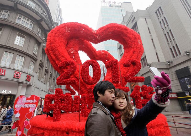 A couple takes a photograph with a mobile phone in front of a red heart decoration on the Valentine's Day in Wuhan, Hubei province February 14, 2012. REUTERS/Stringer (CHINA - Tags: SOCIETY) CHINA OUT. NO COMMERCIAL OR EDITORIAL SALES IN CHINA *** Local Caption ***  PEK04_CHINA-_0214_11.JPG