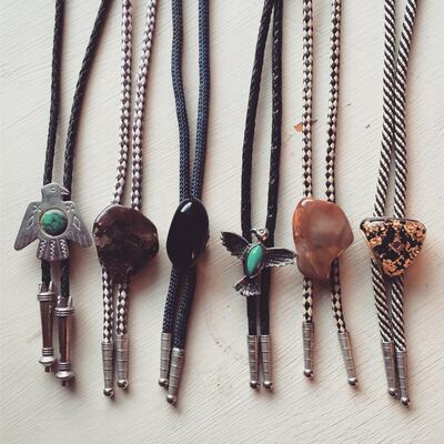 A collection of vintage bolo ties arranged neatly in a row on a white background.