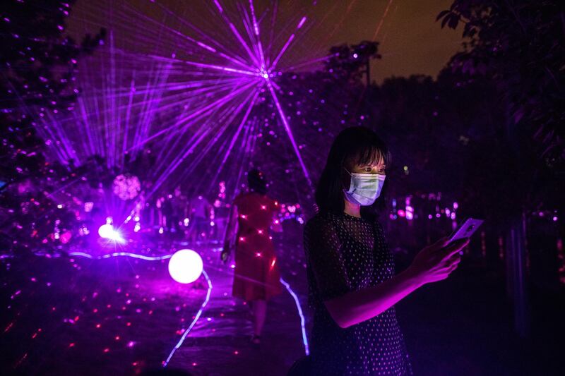 A woman wearing a protective face mask looks at outdoor light shows during the Beijing International Light Festival at the Yuyuantan Park in the Chinese capital.  EPA