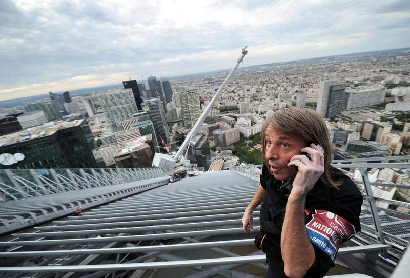 Alain Robert uses his mobile phone after climbing the 231-meter high First Tower, the tallest skyscraper in France, at La Defense district in Courbevoie, outside Paris on May 10, 2012. Franck Fife / AFP Photo
