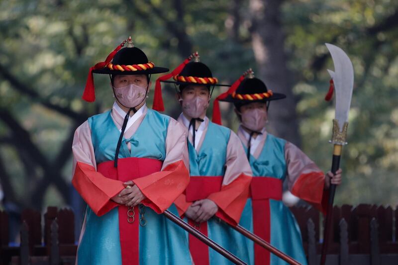 Performers wearing traditional guard uniforms and protective face masks as a precaution against the coronavirus, stand during a re-enactment ceremony of the changing of the Royal Guards, in front of the main gate of the Deoksu Palace in Seoul, South Korea. AP Photo