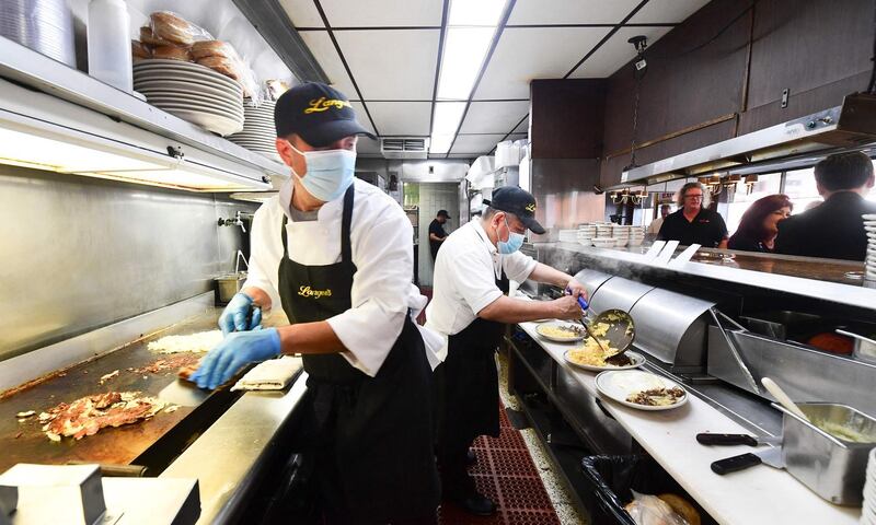 Kitchen staff who are continuing to wear face masks prepare breakfast at Langer's Delicatessen-Restaurant in Los Angeles, California. AFP