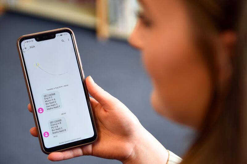A pupil at Stonelaw High School receives a text message with her exam results on her mobile phon in Rutherglen, Glasgow, Scotland, Britain, August 4, 2020. Exams were cancelled in Scotland due to the coronavirus pandemic and pupils have been awarded grades based on assessment. Andy Buchanan/Pool via REUTERS