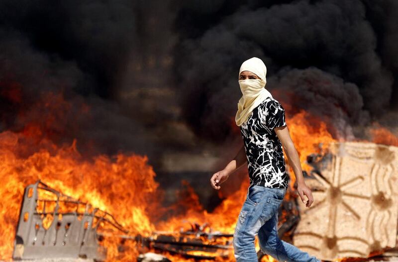 A Palestinian protester walks past a fire during clashes with Israeli troops at a protest in support of Palestinian prisoners on hunger strike in Israeli jails, in the West bank village of Beita, near Nablus. Mohamad Torokman / Reuters