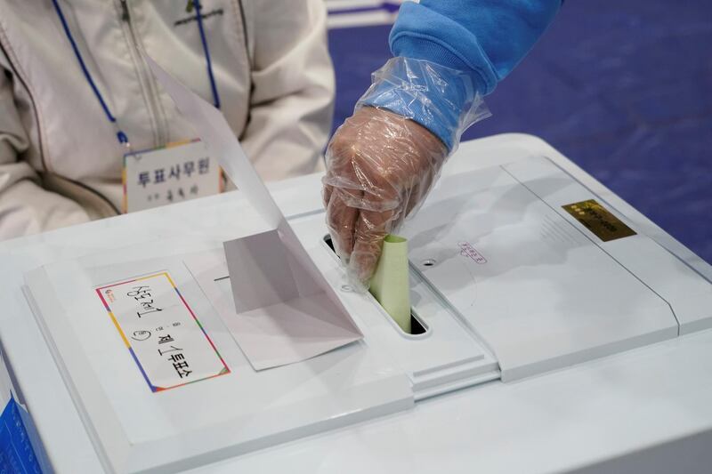 A voter wearing plastic gloves casts a ballot at a polling station in Seoul, South Korea. Reuters