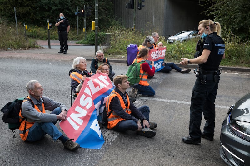 A police officer asks Insulate Britain climate activists to move out of a slip road on the M25. Getty