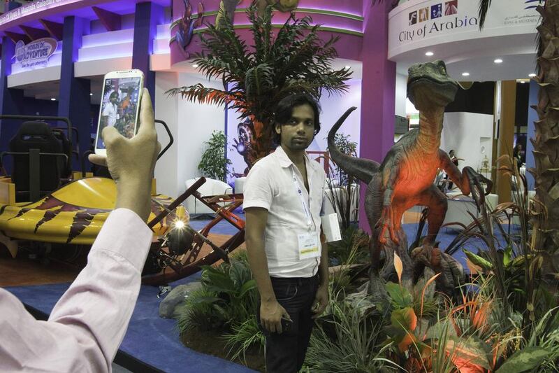 A visitor, one of the 21,000 people expected to go to the Arabian Travel Market event, poses for a souvenir shot beside a toy dinosaur at the IMG showroom. Jaime Puebla / The National