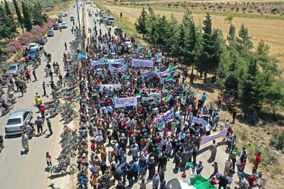 An aerial view taken May 25, 2020 shows Syrian protesters, displaced from their homes in the rebel bastion of Idlib which had been under assault by government forces earlier this year, gathering outside a Turkish army base near Syria's northwestern city of Idlib during a demonstration to demand the Turks fullfil their side of a truce agreement and allow them to return to their homes.  / AFP / Omar HAJ KADOUR
