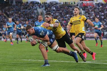 Dalton Papalii of the Blues (L) dives in for a try as the Hurricanes' TJ Perenara tries to tackle during the Super Rugby match between the Auckland Blues and Wellington Hurricanes at Eden Park stadium in Auckland on June 14, 2020. / AFP / MICHAEL BRADLEY